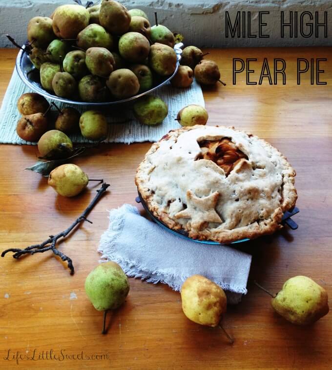 mile high pear pie on a table with a large bowl of pears