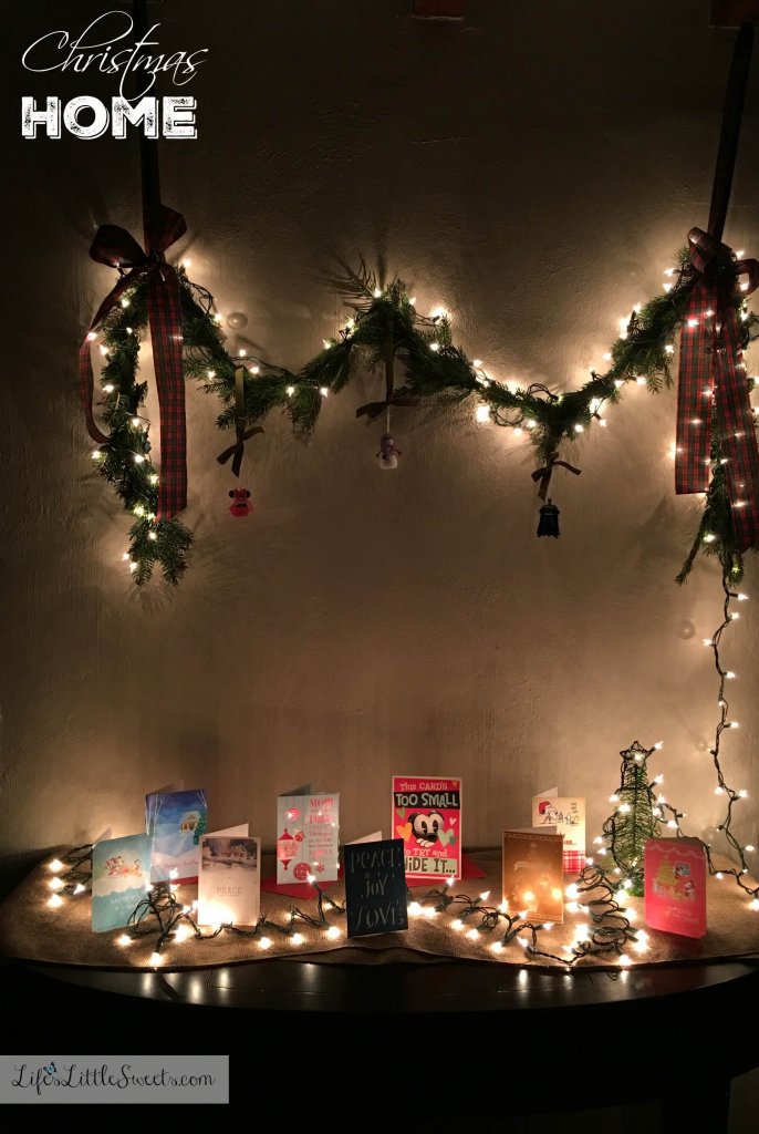 DIY Christmas Garland and Greeting Card Table on a white wall, lit up