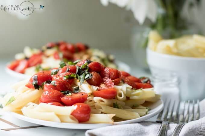 Pan-Fried Tomatoes on top of penne pasta on white plate 