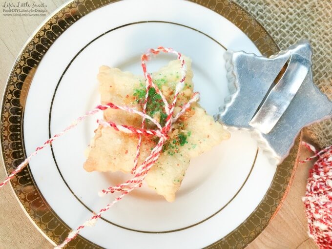 This Sand Tart Cookie Recipe is our family recipe perfect for the Christmas & Holiday season making a big batch of cookies. These cookies are easy to customize to your tastes with various toppings and make a fun activity for everyone involved. Check out our family home VIDEO of our cookie making session. #sandtart #recipe #homemade #cookies #cookie #sugarcookie #Christmas #sprinkles horizontal, overhead image of a stack of star-shaped sand tart cookies ties up with bakers red and white twine with a star-shaped antique cookie cutter