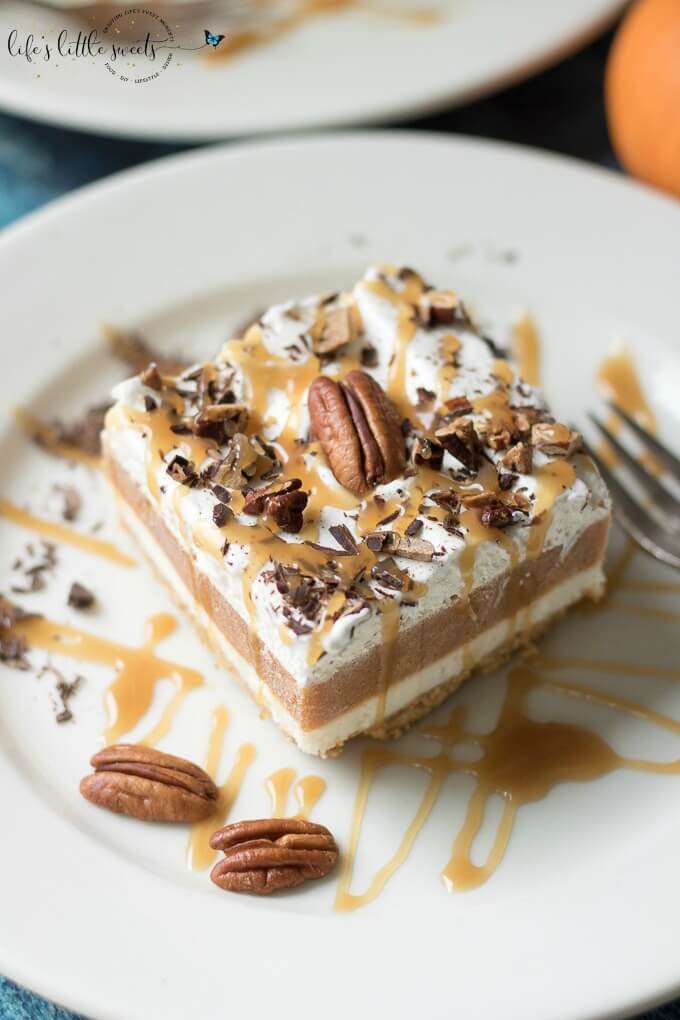This Pumpkin Lasagna Dessert has a vanilla graham cracker crust, a sweet cream cheese layer, pumpkin spice Jello pudding, Cool Whip topping and it's topped with toasted, chopped pecans, shaved bittersweet chocolate and drizzled with caramel sauce. This no bake dessert feeds a crowd, filling a 13 x 9 inch pan; having a slice of this delicious dessert will have you craving more! #lush #dessert #lasagna #pumpkinspicepudding #toastedpecans #bittersweetchocolate #coolwhip #grahamcrackercrust #creamcheese