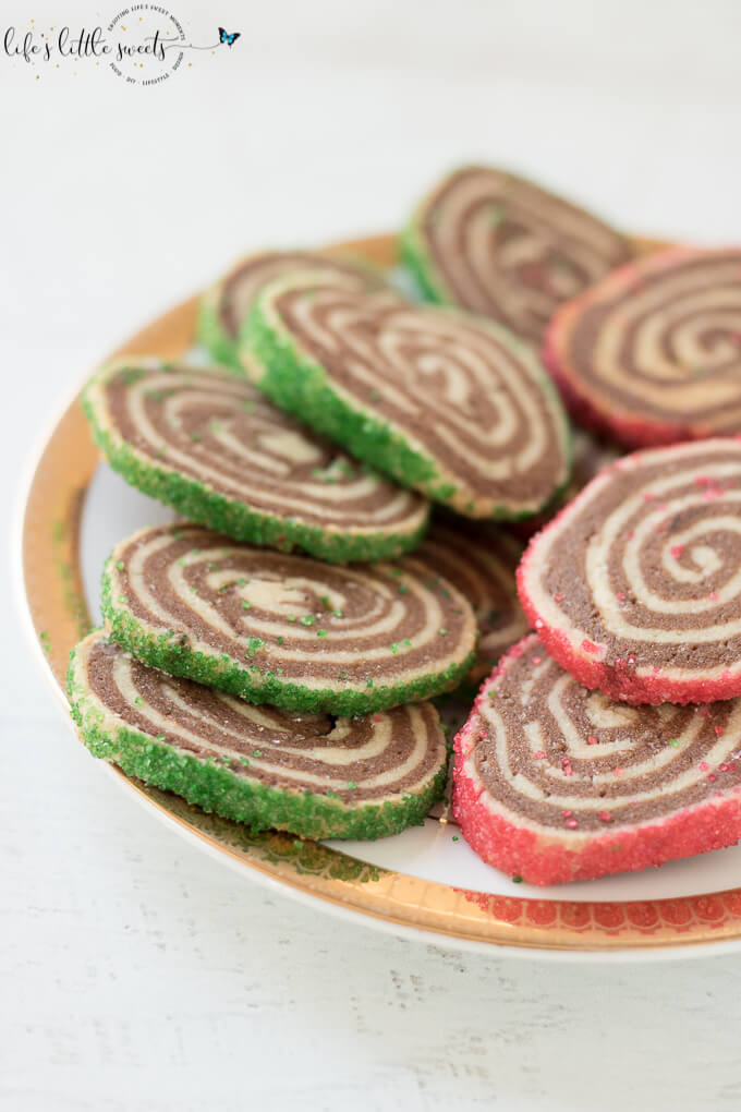 Pinwheel Cookies are perfect for the Christmas holiday season; this family recipe has a dough that can be made ahead and then sliced when ready to make them. They are crisp sugar cookies with alternating vanilla and chocolate dough, and optionally coated in festive sugar sprinkles. #sprinkles #sugarcookies #cookies #christmascookies #holiday #chocolate #christmas #pinwheels #pinwheelcookies #recipe