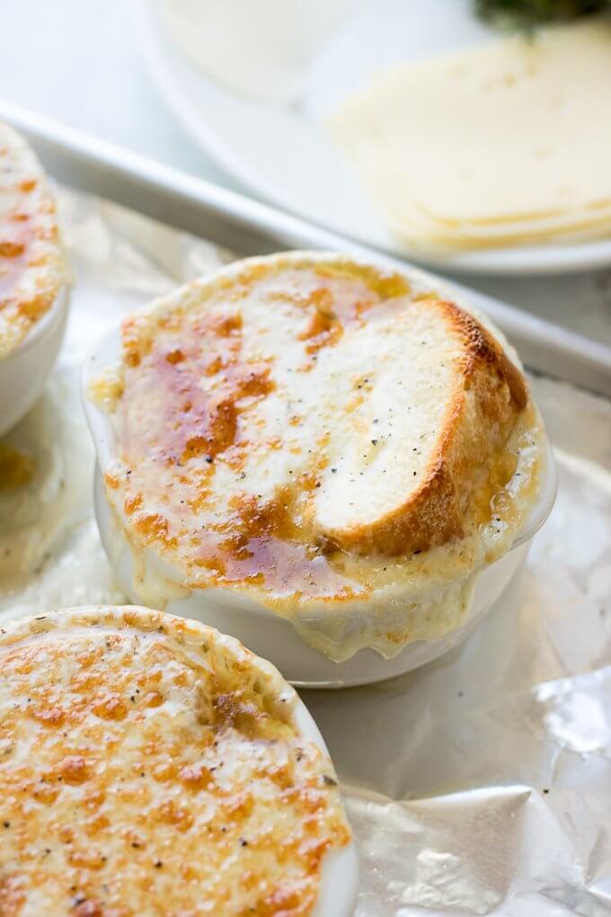 This Homemade French Onion Soup recipe has the flavors of a classic French onion soup that you would find at a restaurant, yet, it is easy to prepare in your home kitchen. Caramelized onions in a reduction of white wine and sherry with herbs of thyme and bay leaves in a clear beef broth make this soup delicious. #onions #Frenchonionsoup #cheese #recipe #Frenchbread #homemade #thyme #garlic #Muentser #Swiss