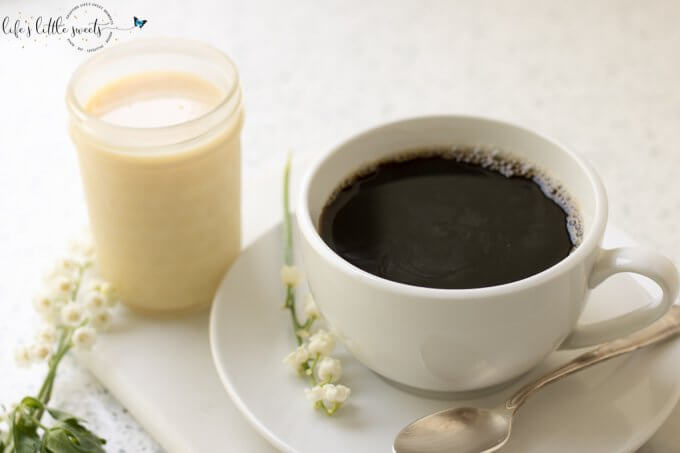 Sweetened Condensed Milk and black coffee with lily of the valley flowers on a white kitchen counter