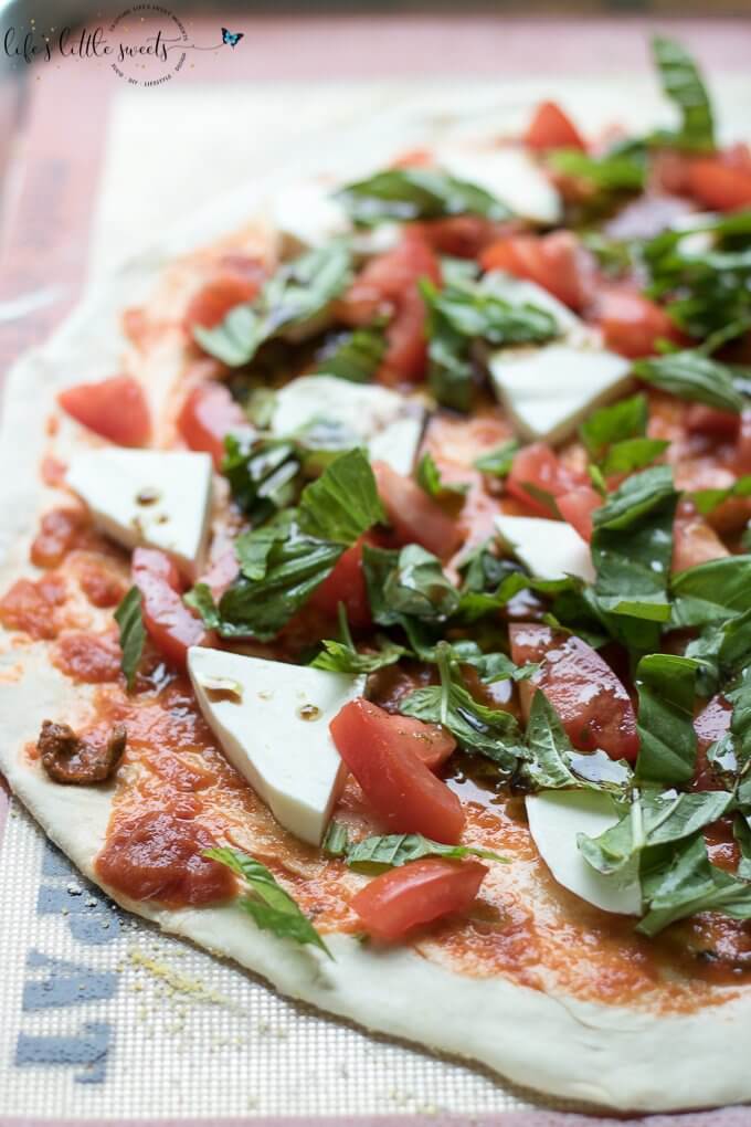 This Caprese Pizza is topped with ripe tomatoes, fresh basil, sliced mozzarella and drizzled with an olive oil-balsamic dressing. Make this homemade pizza for a bistro dinner at home! (makes 2 individual pizzas or 1 large pizza) #tomato #basil #pizza #homemade #recipe #mozzarella