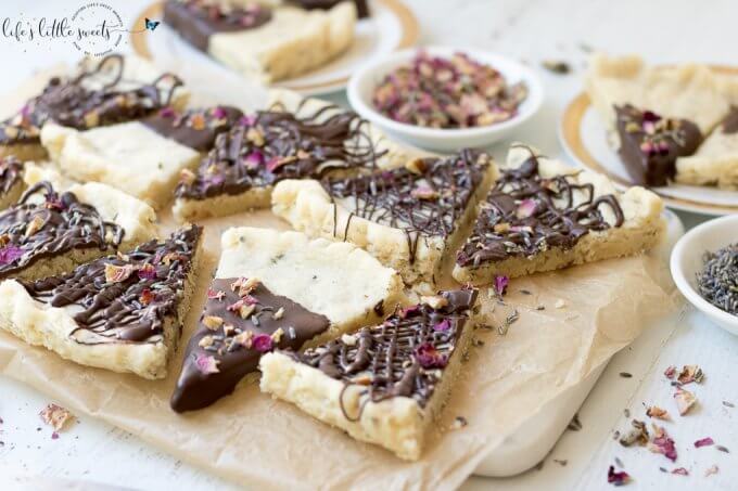 Lavender Rose Shortbread is a herb-infused, classic shortbread cookie, dipped in dark chocolate and decorated with dried lavender and rose petals. #lavender #rose #shortbread #chocolate #edibleflowers #driedflower #driedherbs #roses #cookies #recipe #homemade #butter #flour