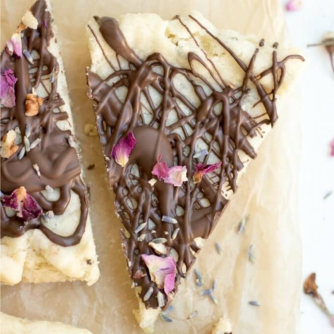 Lavender Rose Shortbread is a herb-infused, classic shortbread cookie, dipped in dark chocolate and decorated with dried lavender and rose petals. #lavender #rose #shortbread #chocolate #edibleflowers #driedflower #driedherbs #roses #cookies #recipe #homemade #butter #flour