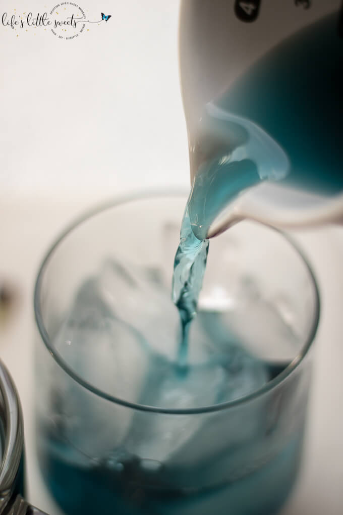 pouring Blue Butterfly Pea Flower Tea in glass on white surface