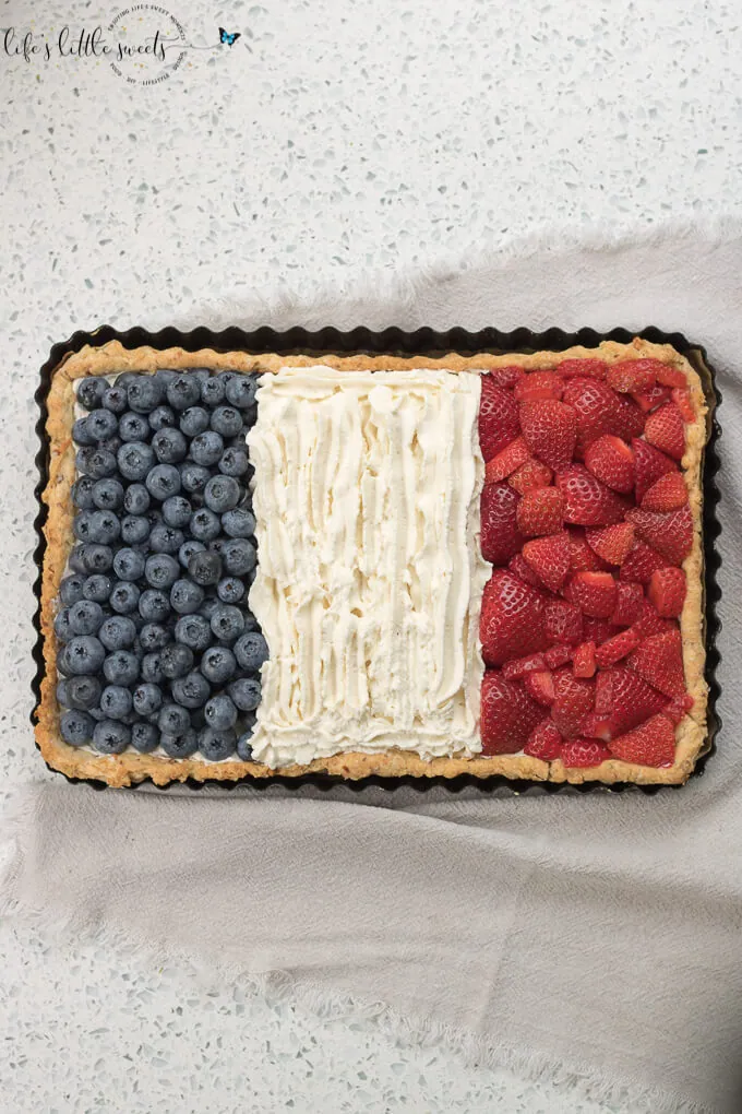 French Flag Tart has a homemade almond pie crust, a rich chocolate ganache filling, homemade, stabilized vanilla whipped cream and fresh, seasonal berries like strawberries and blueberries placed on top, in the symbol of the French Flag. #French #Frenchflagtart #tart #recipe #ganache #chocolate #espresso #coffee #berries #fruit #whippedcream #almond