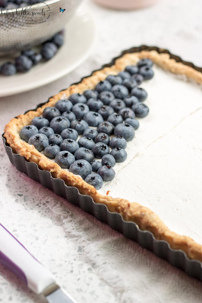 French Flag Tart has a homemade almond pie crust, a rich chocolate ganache filling, homemade, stabilized vanilla whipped cream and fresh, seasonal berries like strawberries and blueberries placed on top, in the symbol of the French Flag. #French #Frenchflagtart #tart #recipe #ganache #chocolate #espresso #coffee #berries #fruit #whippedcream #almond