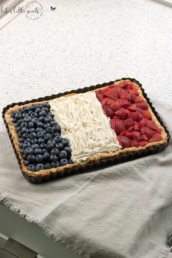French Flag Tart has a homemade almond pie crust, a rich chocolate ganache filling, homemade, stabilized vanilla whipped cream and fresh, seasonal berries like strawberries and blueberries placed on top, in the symbol of the French Flag. #French #Frenchflagtart #tart #recipe #ganache #chocolate #espresso #coffee #berries #fruit #whippedcream #almond