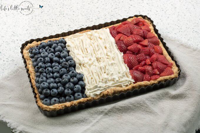 French Flag Tart has a homemade almond pie crust, a rich chocolate ganache filling, homemade, stabilized vanilla whipped cream and fresh, seasonal berries like strawberries and blueberries placed on top, in the symbol of the French Flag. #French #Frenchflagtart #tart #recipe #ganache #chocolate #espresso #coffee #berries #fruit #whippedcream #almond