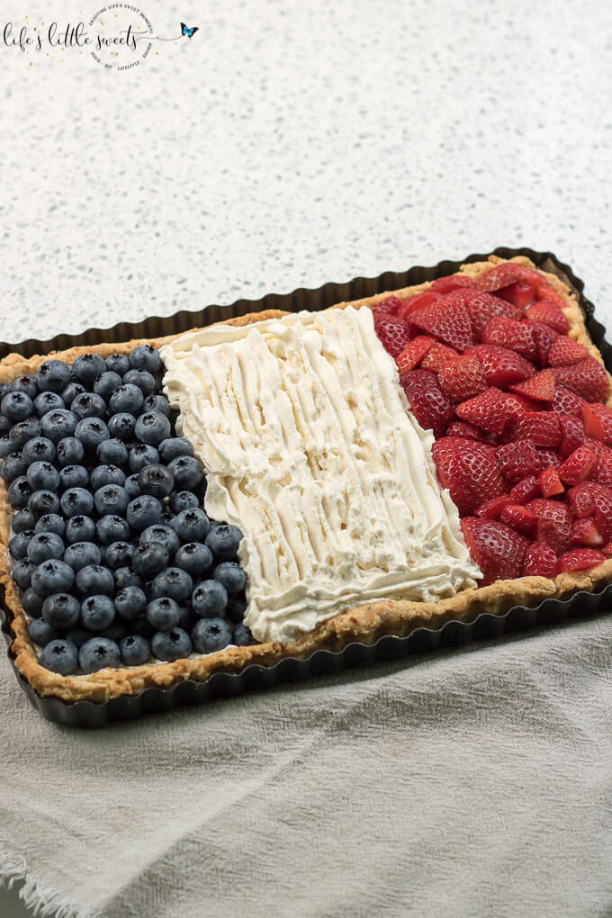 French Flag Tart has a homemade almond pie crust, a rich chocolate ganache filling, homemade, stabilized vanilla whipped cream and fresh, seasonal berries like strawberries and blueberries placed on top, in the symbol of the French Flag. #French #Frenchflagtart #tart #recipe #ganache #chocolate #espresso #coffee #berries #fruit #whippedcream #almond