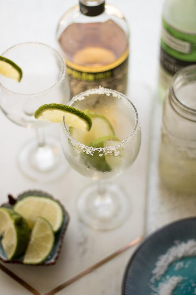 (msg 21+) This classic, Margarita recipe tastes like Summer with fresh lime juice, margarita mixer, tequila and served in a chilled glass, rimmed with Mediterranean salt crystals and lime slices. #lime #margarita #seasalt #ice #drink