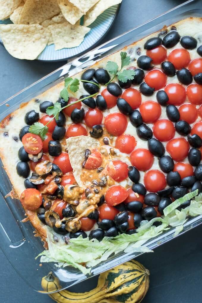 #ad - This easy 7 Layer Dip recipe is savory, meaty, and baked to cheesy perfection. It feeds a crowd in a 9 x 13 inch dish making it perfect for any gathering; you will find guests clamoring for more! #RotelDareToDip #CollectiveBias #7layerdip #hotdip #diprecipes