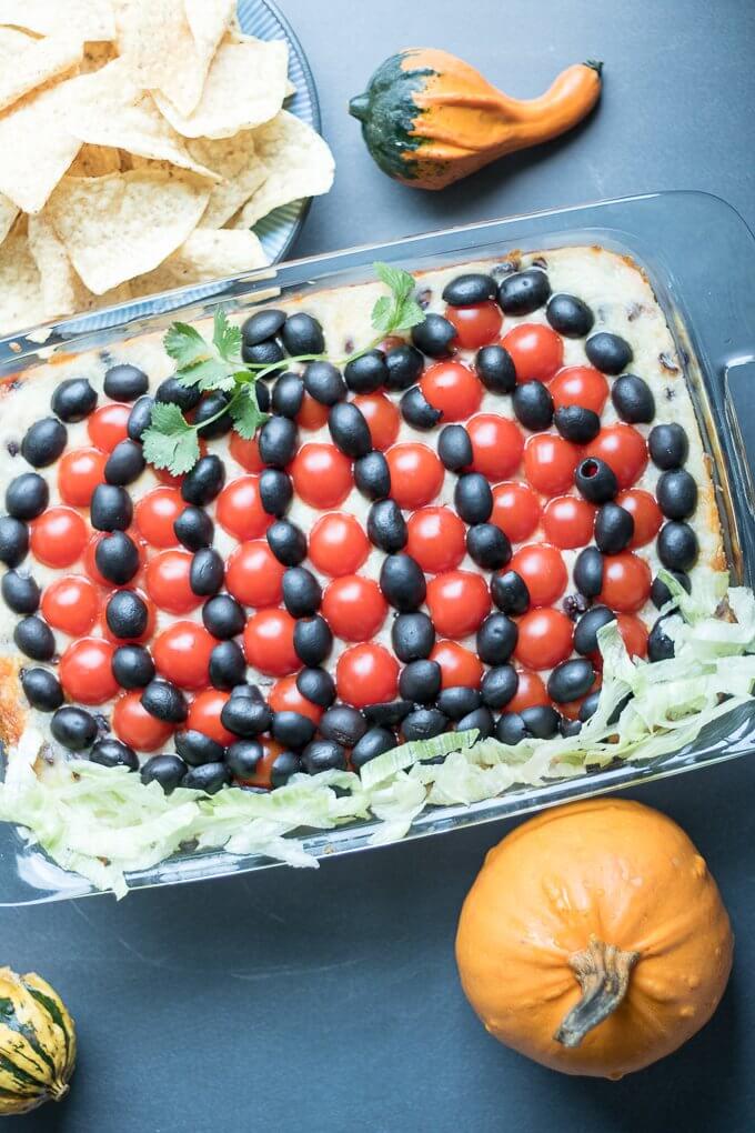 #ad - This easy 7 Layer Dip recipe is savory, meaty, and baked to cheesy perfection. It feeds a crowd in a 9 x 13 inch dish making it perfect for any gathering; you will find guests clamoring for more! #RotelDareToDip #CollectiveBias #7layerdip #hotdip #diprecipes