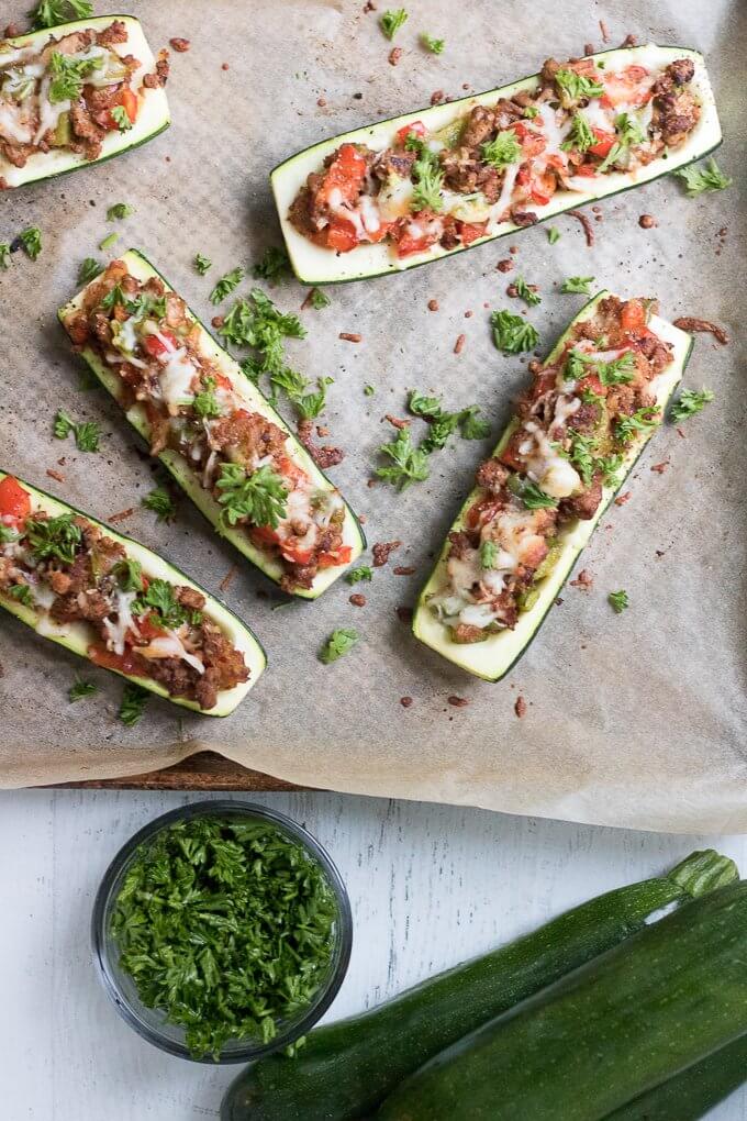 These Stuffed Zucchini Boats are a savory, delicious and complete dinner allowing you to get your dose of vegetables. Filled with your favorite meat, in this case, lean ground turkey, they also have bell peppers, onions and grated cheese. This low-carb dinner is a great way to use up all that garden zucchini! #zucchini #zucchiniboats #squash #turkey #cheese #parsley #onions #peppers