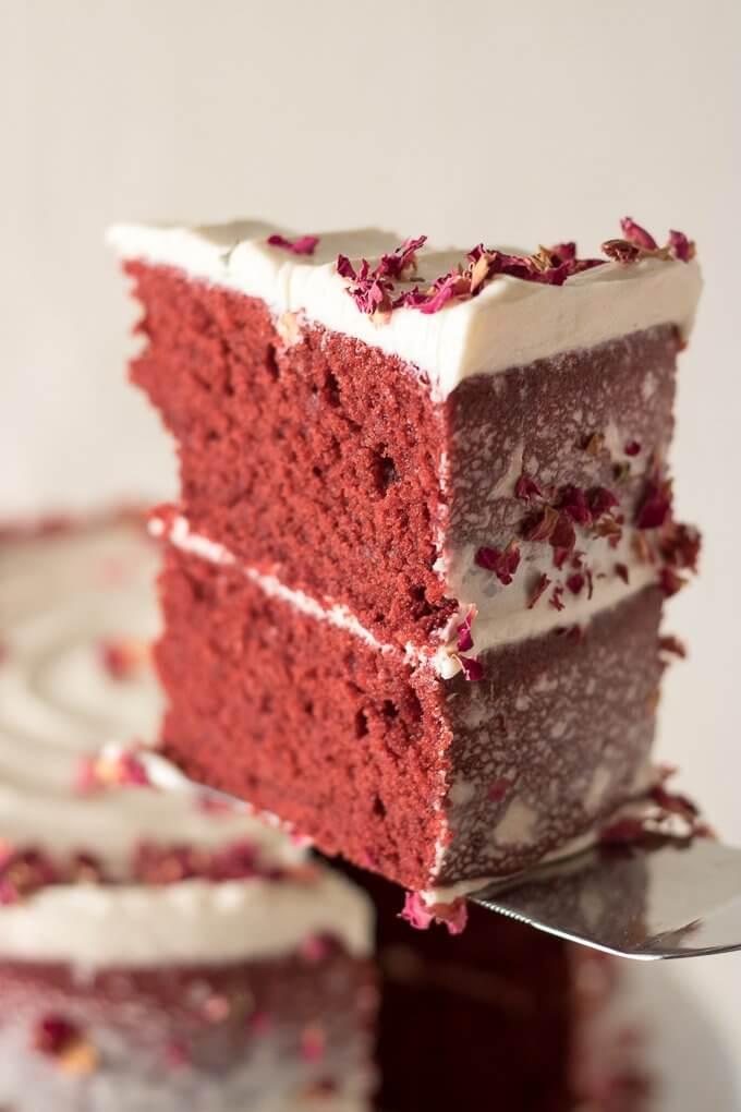 This Red Velvet Cake Recipe is a tall, dramatic, 2-tiered cake recipe that uses red cocoa, espresso powder, and is topped with a delicious cream cheese frosting. This cake is festive, attractive and perfect for year-round celebrations, birthdays and gatherings! #redvelvet #cake #recipe #creamcheese #frosting #roses #rosecake #nakedcake