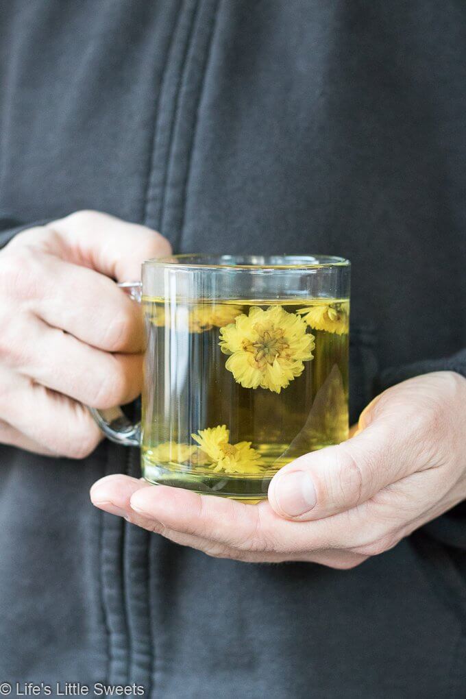 Hands holding a mug of hot Chrysanthemum Flower Tea 