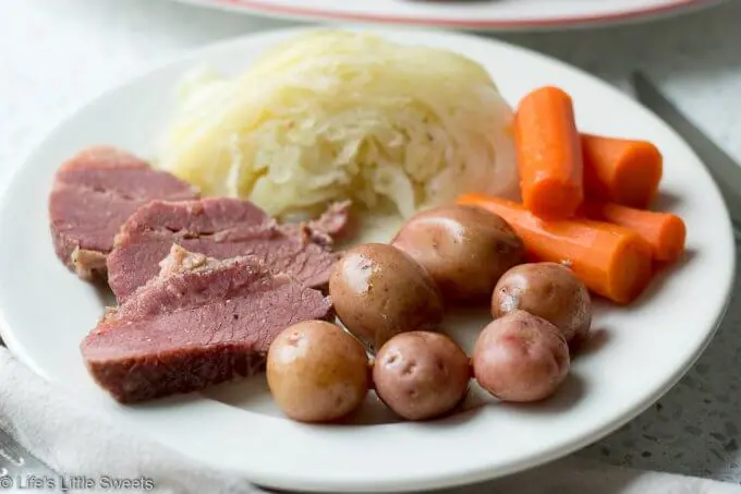 Corned Beef and Cabbage is a classic Irish-American family dinner popular to serve on St. Patrick's Day. This savory, delicious and complete meal is cooked in a Dutch Oven on the stove top with corned beef brisket, baby red potatoes, green cabbage wedges and carrots. #cornedbeefandcabbage #stpatricksday #carrots #redpotatoes #recipe #greencabbage #cabbage #Dutchoven #brisket