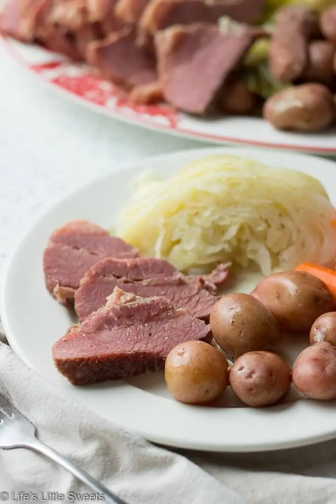 Corned Beef and Cabbage is a classic Irish-American family dinner popular to serve on St. Patrick's Day. This savory, delicious and complete meal is cooked in a Dutch Oven on the stove top with corned beef brisket, baby red potatoes, green cabbage wedges and carrots. #cornedbeefandcabbage #stpatricksday #carrots #redpotatoes #recipe #greencabbage #cabbage #Dutchoven #brisket