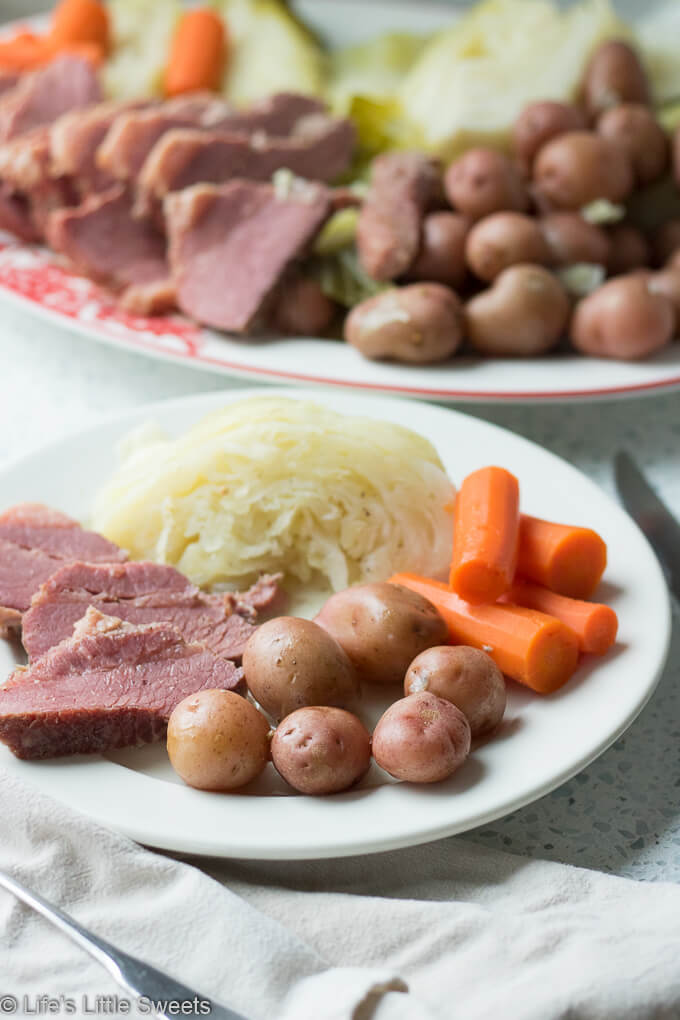 Corned Beef and Cabbage is a classic Irish-American family dinner popular to serve on St. Patrick's Day. This savory, delicious and complete meal is cooked in a Dutch Oven on the stove top with corned beef brisket, baby red potatoes, green cabbage wedges and carrots. #cornedbeefandcabbage #stpatricksday #carrots #redpotatoes #recipe #greencabbage #cabbage #Dutchoven #brisket