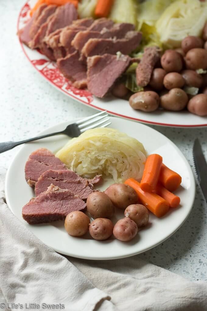 Corned Beef and Cabbage is a classic Irish-American family dinner popular to serve on St. Patrick's Day. This savory, delicious and complete meal is cooked in a Dutch Oven on the stove top with corned beef brisket, baby red potatoes, green cabbage wedges and carrots. #cornedbeefandcabbage #stpatricksday #carrots #redpotatoes #recipe #greencabbage #cabbage #Dutchoven #brisket