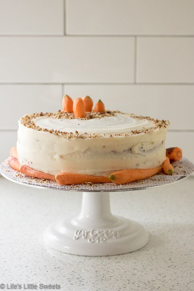 Homemade Classic Carrot Cake with Cream Cheese Frosting has cinnamon, vanilla and 3 cups of finely shredded carrots throughout this delicious cake. It is a 2-tiered cake with smooth and sweet homemade cream cheese frosting. It's topped with optional chopped pecans and decorated with fresh, peeled little carrots. #carrotcake #Eastercake #Easterfood #carrot #carrots #dessert #pecans #sweet