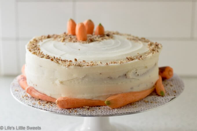 Homemade Classic Carrot Cake with Cream Cheese Frosting has cinnamon, vanilla and 3 cups of finely shredded carrots throughout this delicious cake. It is a 2-tiered cake with smooth and sweet homemade cream cheese frosting. It's topped with optional chopped pecans and decorated with fresh, peeled little carrots. #carrotcake #Eastercake #Easterfood #carrot #carrots #dessert #pecans #sweet