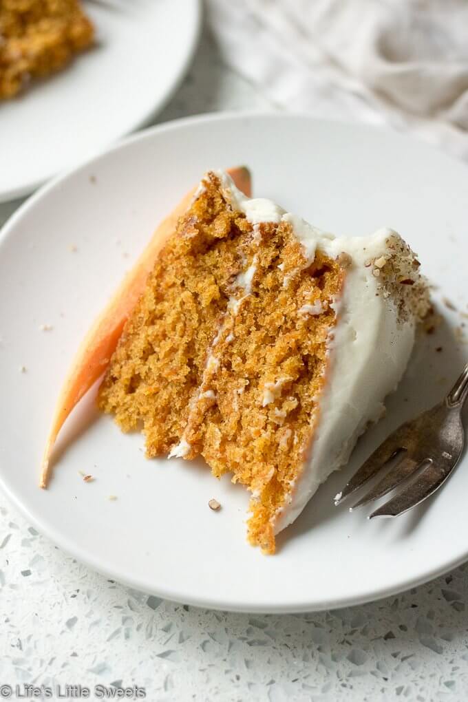 Homemade Classic Carrot Cake with Cream Cheese Frosting has cinnamon, vanilla and 3 cups of finely shredded carrots throughout this delicious cake. It is a 2-tiered cake with smooth and sweet homemade cream cheese frosting. It's topped with optional chopped pecans and decorated with fresh, peeled little carrots. #carrotcake #Eastercake #Easterfood #carrot #carrots #dessert #pecans #sweet