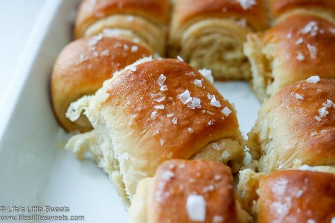 This Parker House Rolls recipe has Maple Butter and Flakey Mediterranean Sea Salt sprinkled on top. These sweet-savory rolls are a solid yeast, bread roll recipe for any occasion or holiday. #parkerhouserolls #bread #rolls #maplebutter #seasalt #dinnerrolls #butter #bread lifeslittlesweets.com