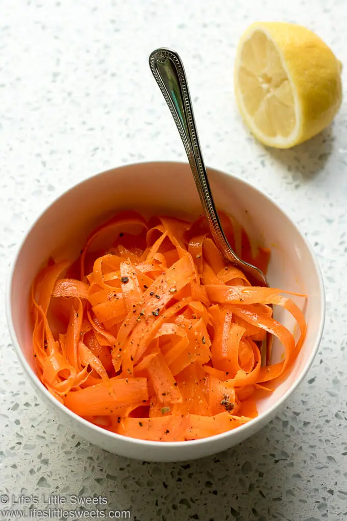 Carrot Ribbon Salad in a white bowl with a lemon