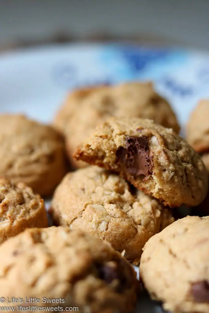 a cookie on top of a pile of chocolate chip cookies with a bite taken out of it