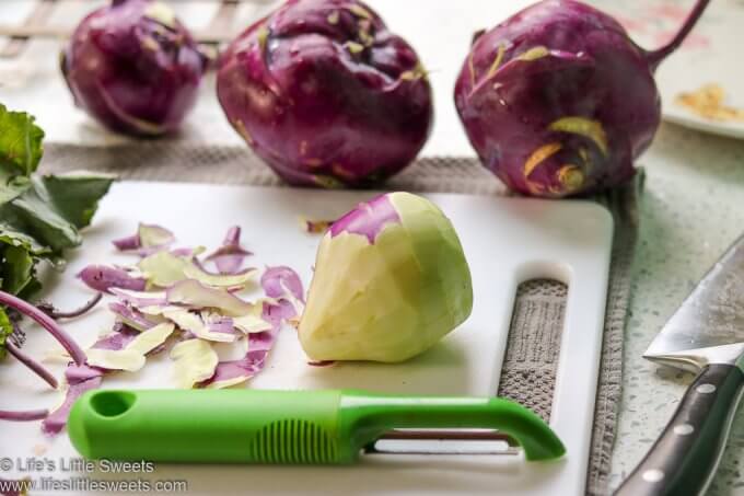 fresh kohlrabi and a vegetable peeler on a cutting board
