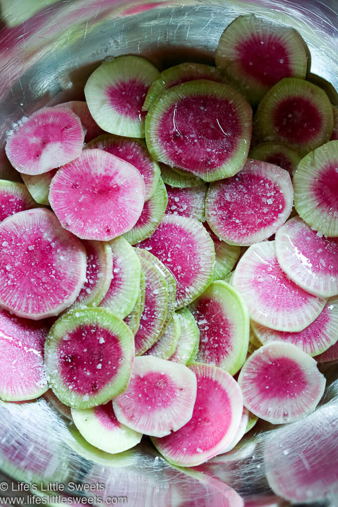 Watermelon Radish slices with seasonings in a metal mixing bowl