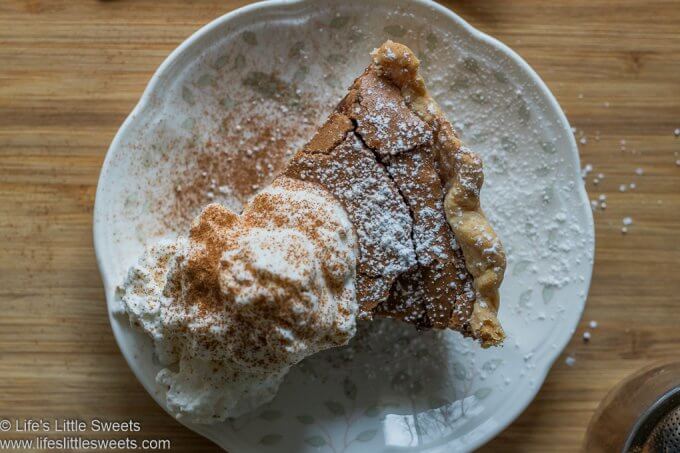 Chocolate Chess Pie with whipped cream on a white place over a wood board