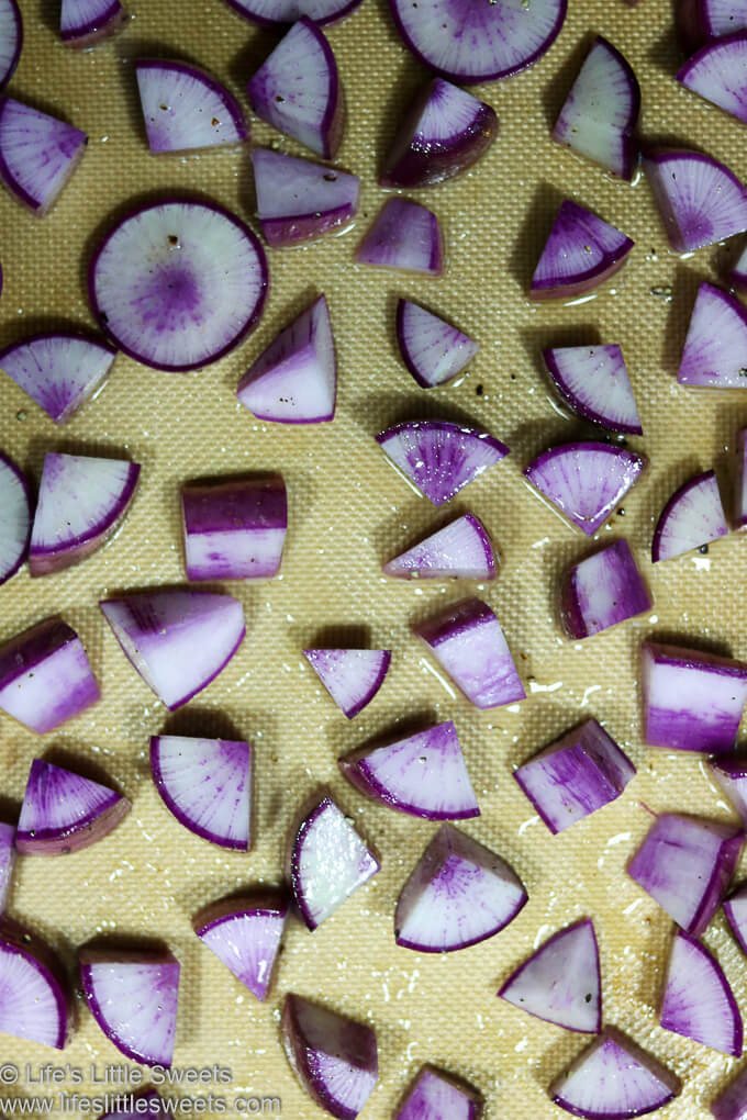 Prepared Purple Daikon Radishes on a lined rimmed baking sheet before being roasted in the oven