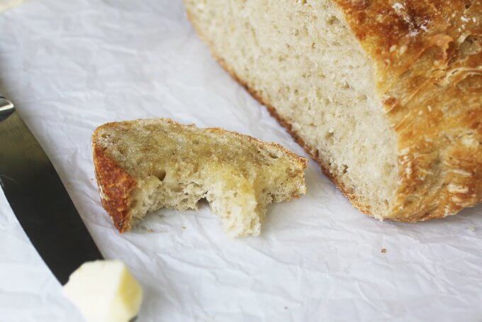 No-Knead Oatmeal Bread slice with a bite and a pat of butter on a knife
