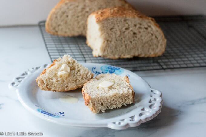 two pieces of no knead oatmeal bread sitting on a plate with butter