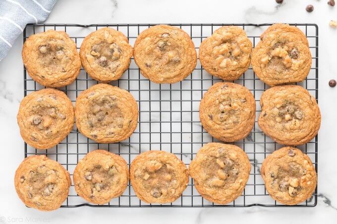 Chocolate Chip Cookies on a wire cooling wrack with one cookie missing on a white marble countertop