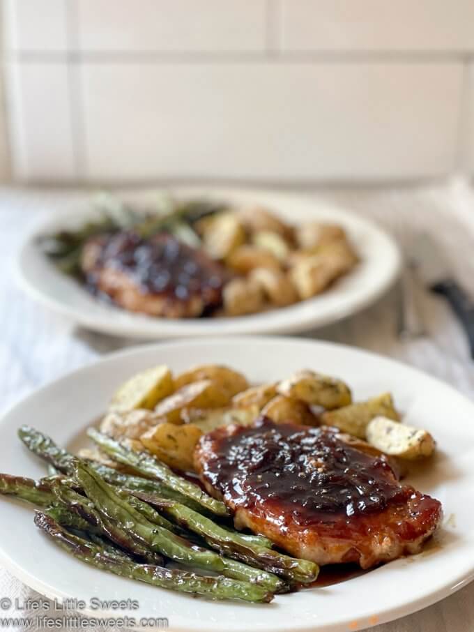 Pork chop dinner with roasted green beans and roasted potatoes on a white plate