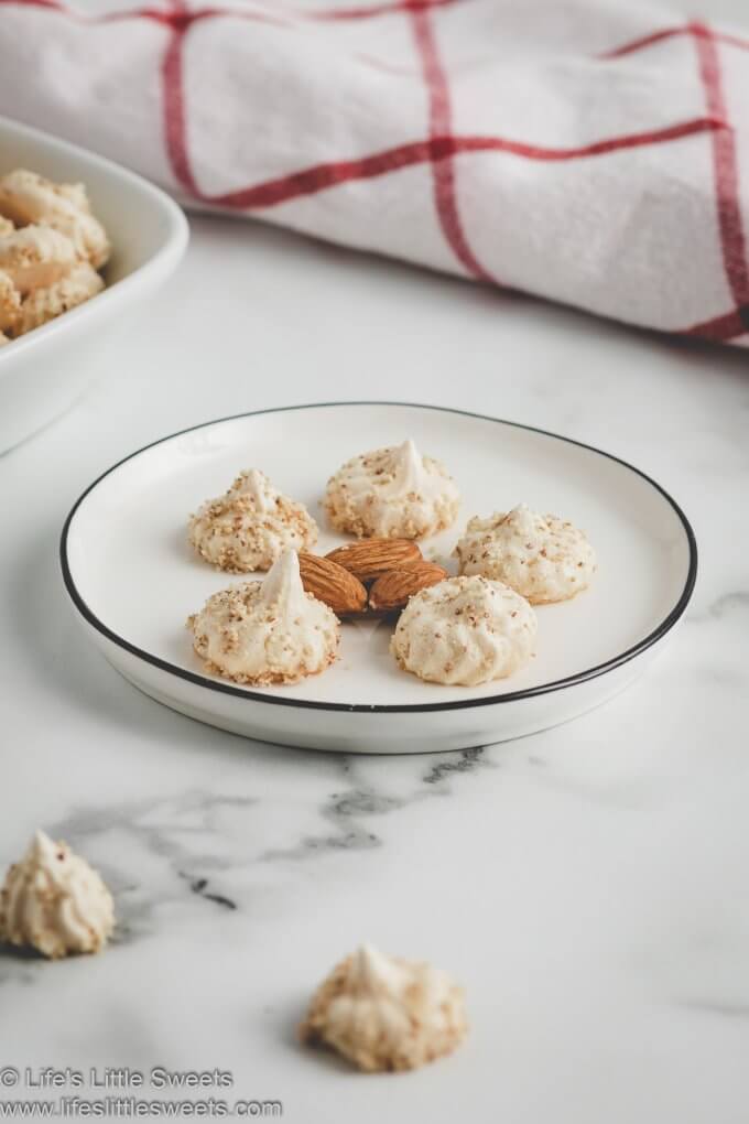 almond meringue kisses on a white plate with almonds