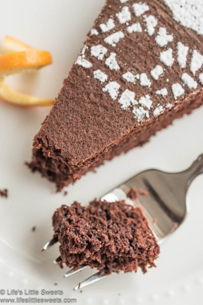 Chocolate Orange Almond Cake slice on a white plate with a fork full of a cake bite