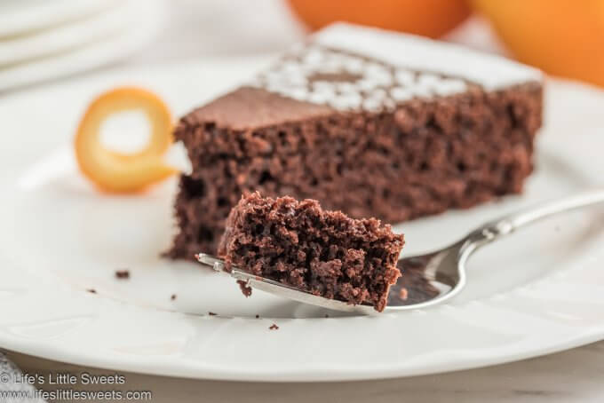 Chocolate Orange Almond Cake slice on a white plate with a fork of cake