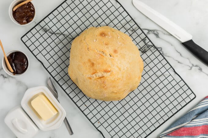 No-Knead Bread (Dutch Oven) on a wire baking mat with butter and jam