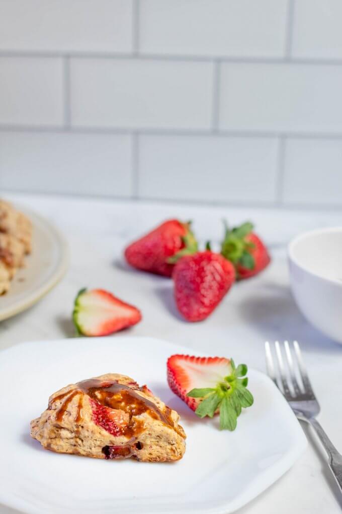 Vegan Soft Strawberry Scones on a white plate in a white kitchen with strawberries in the background