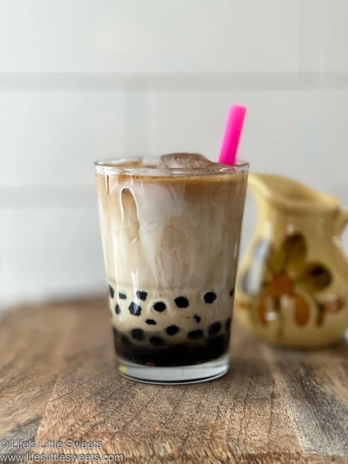 Bubble Coffee Recipe (Boba Coffee) with a pink straw on a wood surface with white subway tile behind