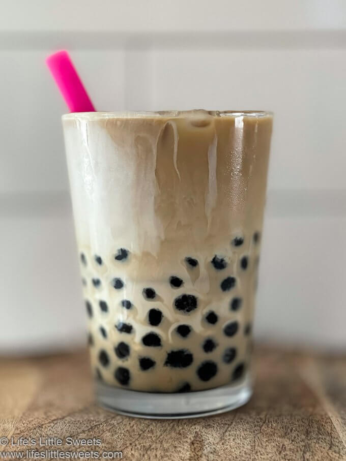 Bubble Coffee Recipe (Boba Coffee) with a pink straw on a wood surface with white subway tile behind