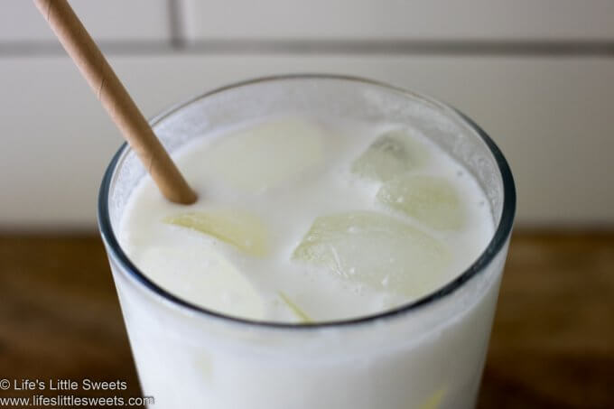 close up of milk powder milk in glass with ice and a cardboard straw 