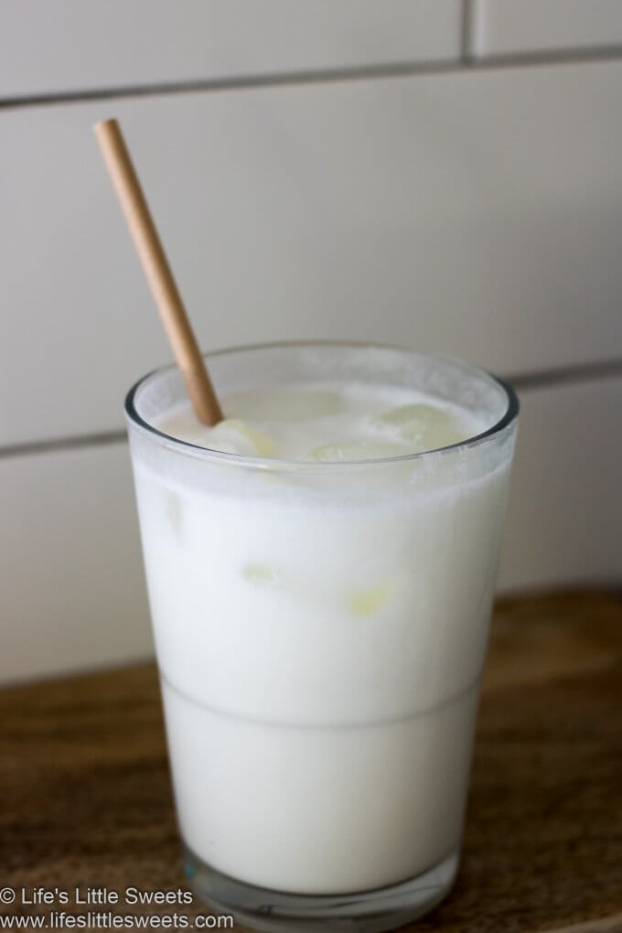 Milk in a glass with a paper straw up close